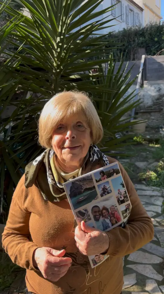 Une grand-mère souriante dans son jardin, tenant fièrement son magazine familial Mamie Jacotte